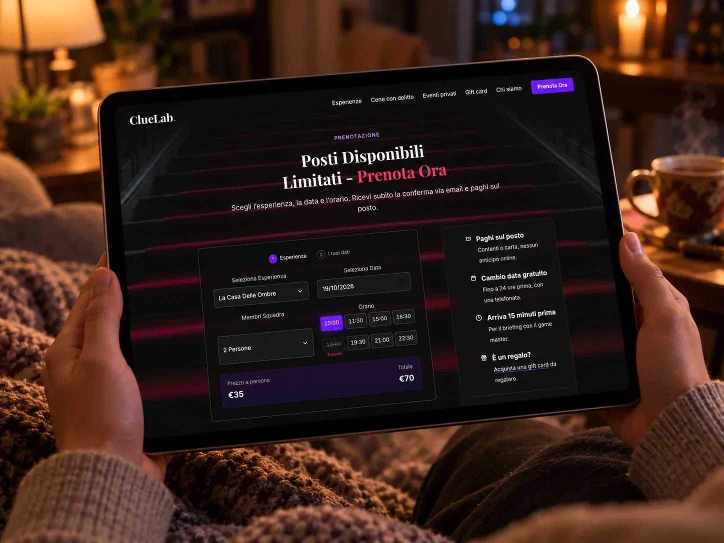 Mani che tengono un tablet con la pagina di prenotazione: esperienza, data, squadra, orari con uno esaurito, prezzo a persona e totale