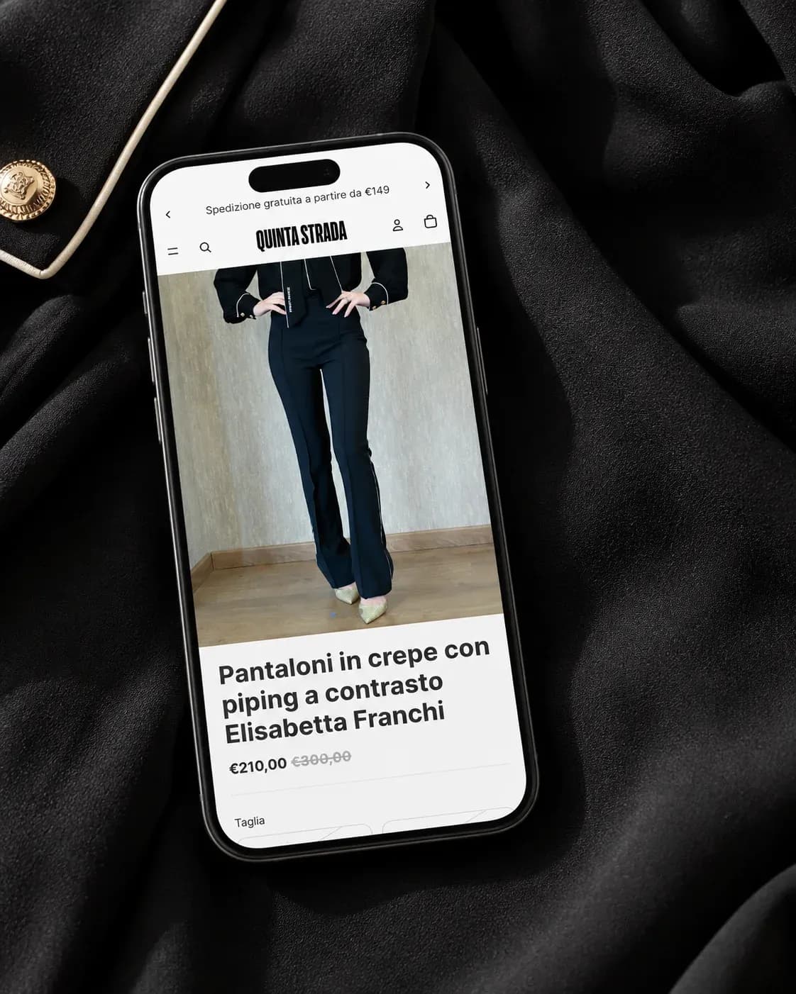 Scheda prodotto mobile di Quinta Strada su uno smartphone appoggiato su tessuto in crêpe nera