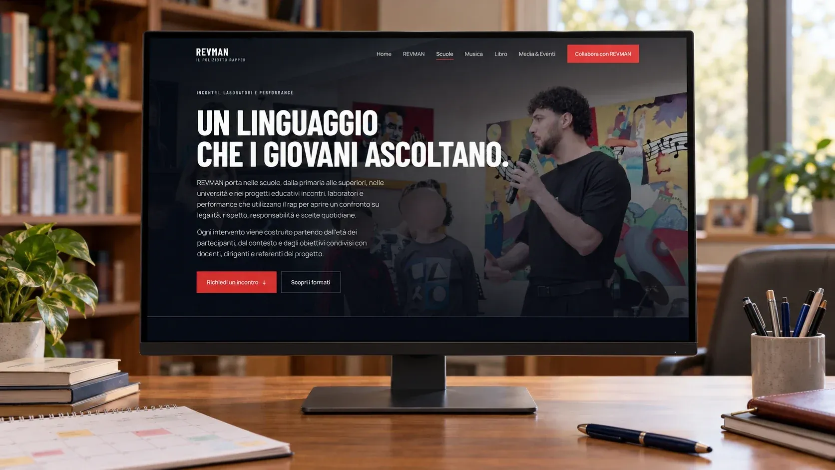 Pagina Scuole del sito di REVMAN su un monitor nell'ufficio di un dirigente scolastico, con il titolo "Un linguaggio che i giovani ascoltano"