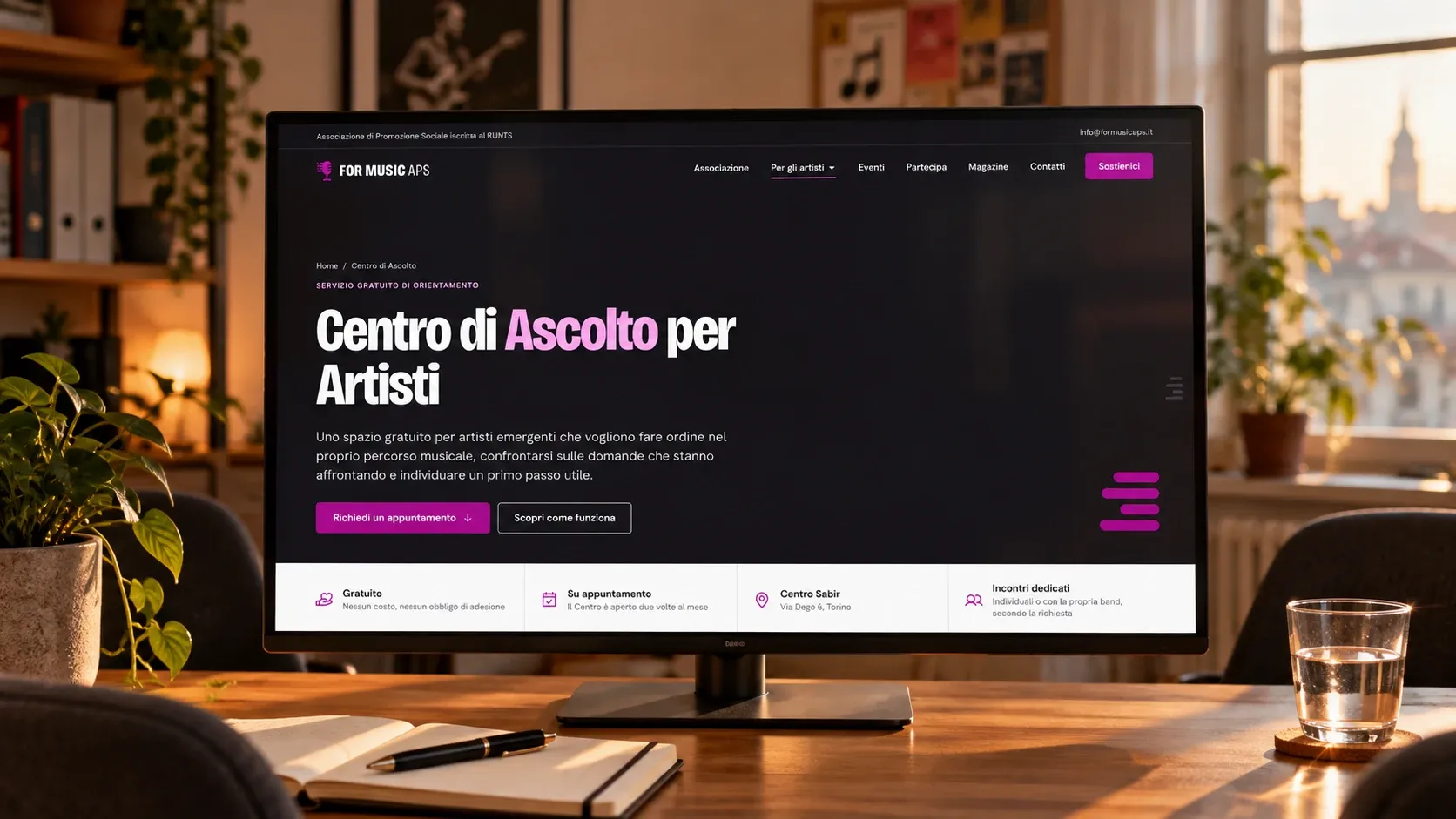 Pagina del Centro di Ascolto per Artisti su un monitor in un piccolo ufficio, con il pulsante per richiedere un appuntamento